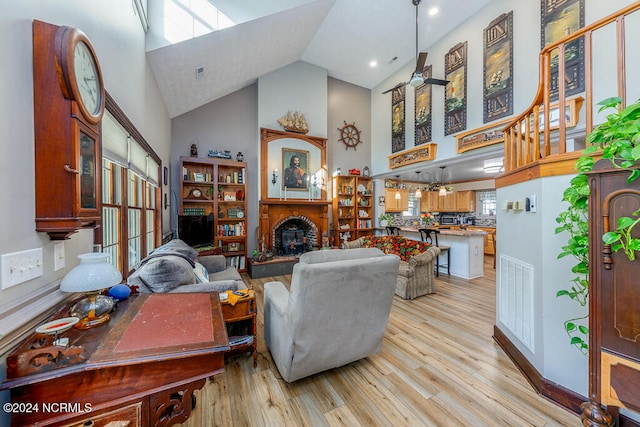 living room with ceiling fan, high vaulted ceiling, and light hardwood / wood-style flooring