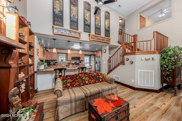 living room featuring light hardwood / wood-style flooring, high vaulted ceiling, and ceiling fan