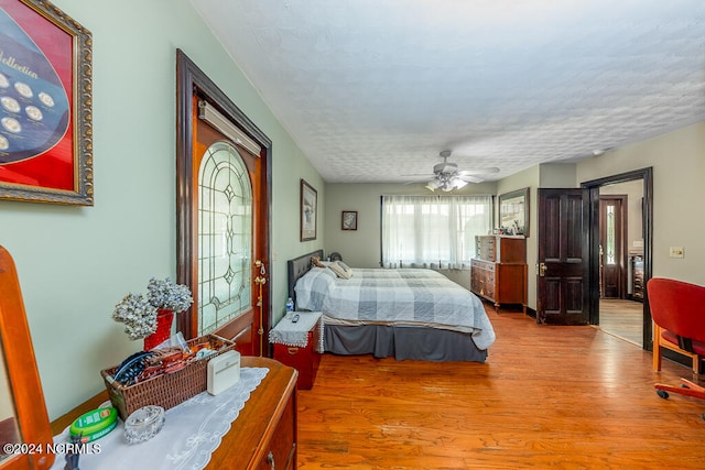 bedroom featuring light hardwood / wood-style flooring, a textured ceiling, and ceiling fan