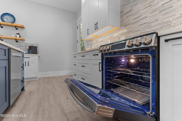 kitchen with decorative backsplash, white cabinetry, beverage cooler, and light wood-type flooring