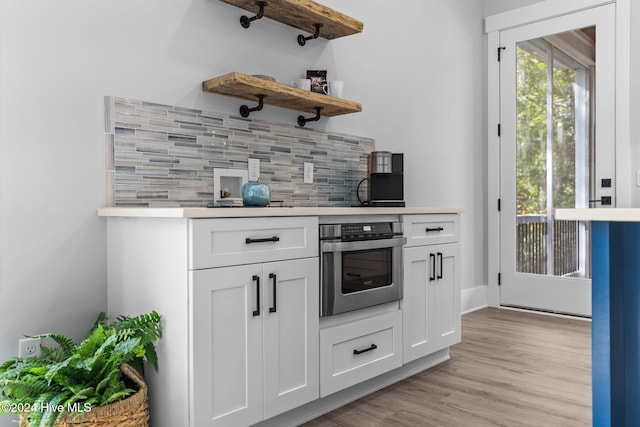 kitchen featuring oven, tasteful backsplash, white cabinetry, and light hardwood / wood-style floors