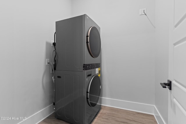 clothes washing area with wood-type flooring and stacked washing maching and dryer