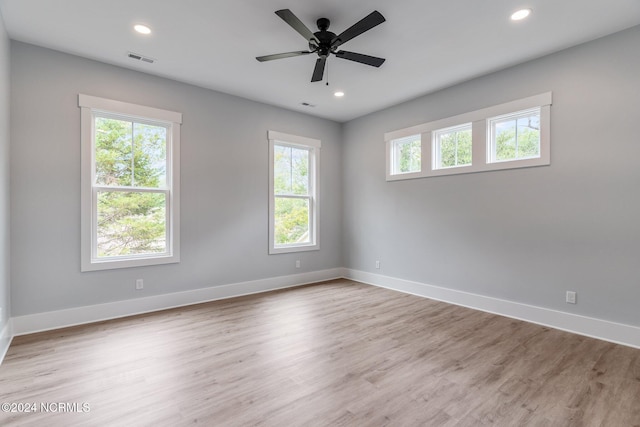 empty room with ceiling fan, a healthy amount of sunlight, and light wood-type flooring