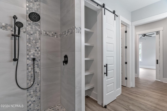 bathroom with hardwood / wood-style flooring, ceiling fan, and tiled shower