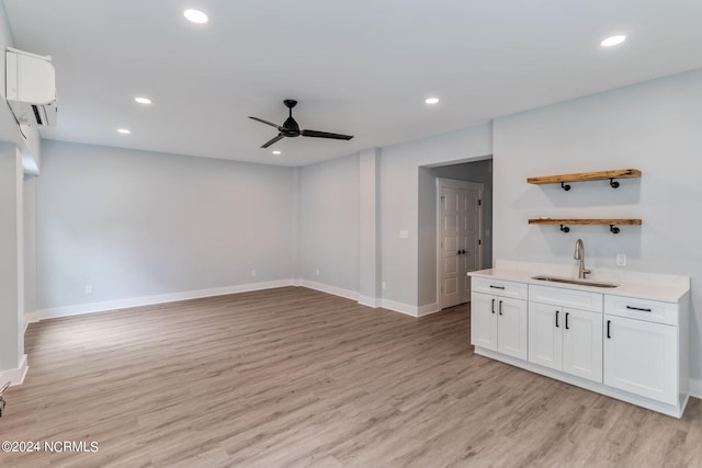 interior space featuring a wall unit AC, ceiling fan, sink, and light hardwood / wood-style floors