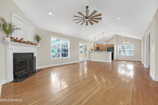 unfurnished living room with light hardwood / wood-style floors, ceiling fan with notable chandelier, and vaulted ceiling