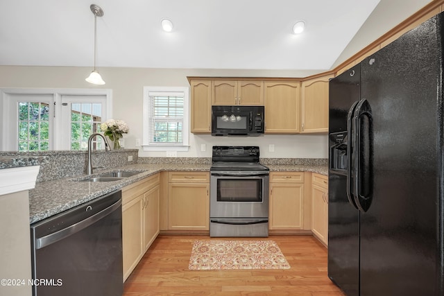 kitchen featuring light brown cabinetry, light wood-type flooring, vaulted ceiling, black appliances, and sink