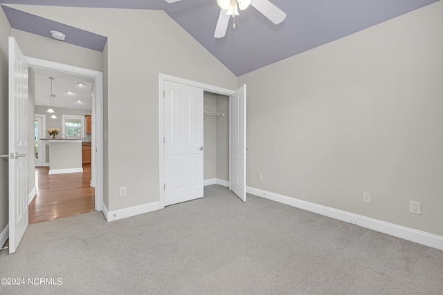 unfurnished bedroom with carpet, vaulted ceiling, a closet, and ceiling fan