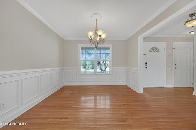 unfurnished dining area with ornamental molding, a notable chandelier, and light wood-type flooring