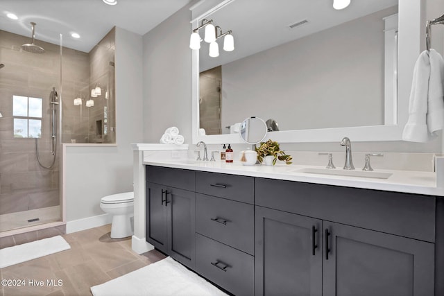 bathroom featuring a tile shower, vanity, and toilet