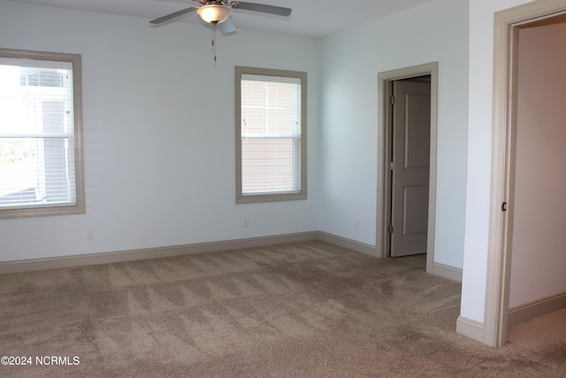 unfurnished room featuring ceiling fan, light carpet, and plenty of natural light