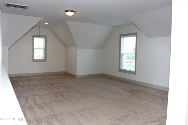 additional living space with vaulted ceiling and light carpet