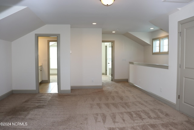 additional living space with lofted ceiling and light carpet