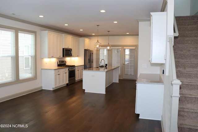 kitchen with sink, an island with sink, hanging light fixtures, appliances with stainless steel finishes, and dark hardwood / wood-style flooring