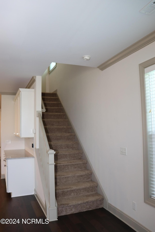 staircase featuring wood-type flooring and crown molding