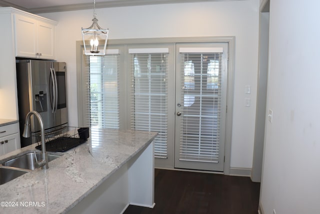 kitchen with light stone counters, hanging light fixtures, white cabinetry, stainless steel refrigerator with ice dispenser, and crown molding