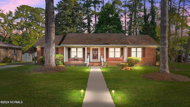 ranch-style house featuring a porch, a storage shed, and a yard