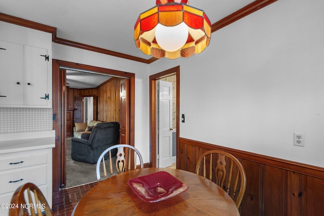 dining room with crown molding and wood walls