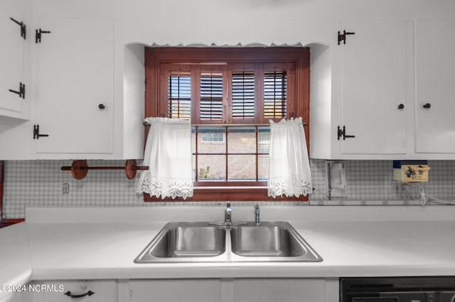 kitchen with white cabinetry, backsplash, and sink