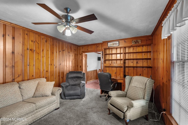 carpeted living room with crown molding, ceiling fan, a textured ceiling, and wood walls