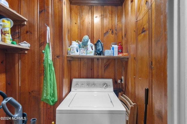 clothes washing area with washer / dryer and wood walls