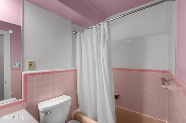 bathroom featuring toilet, shower / tub combo with curtain, and tile walls