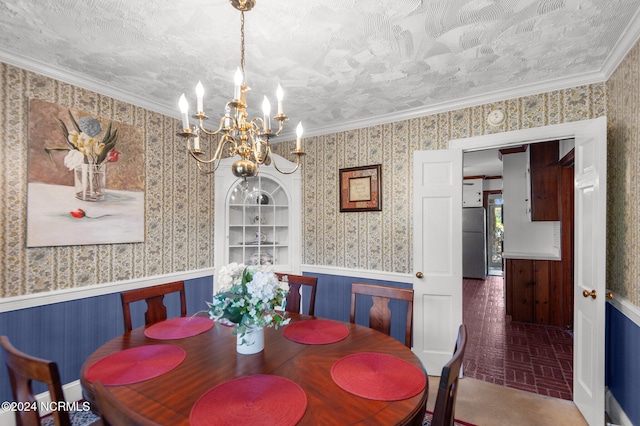 dining room featuring crown molding, a notable chandelier, a textured ceiling, and wooden walls