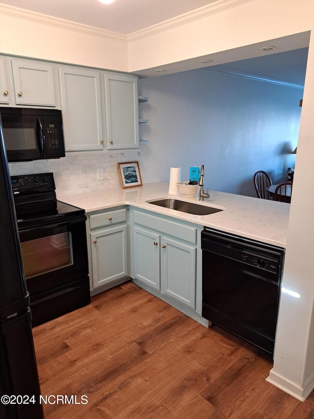 kitchen with light wood-type flooring, sink, tasteful backsplash, and black appliances