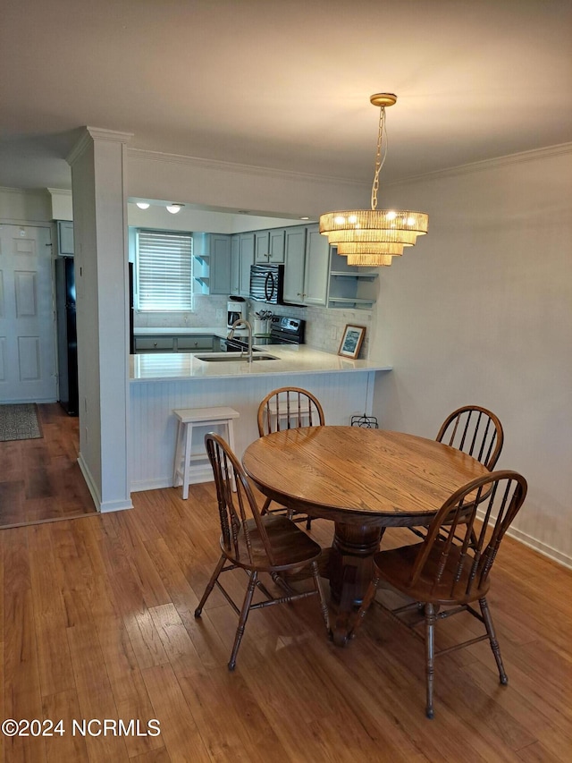 dining area with crown molding, hardwood / wood-style floors, a chandelier, and sink