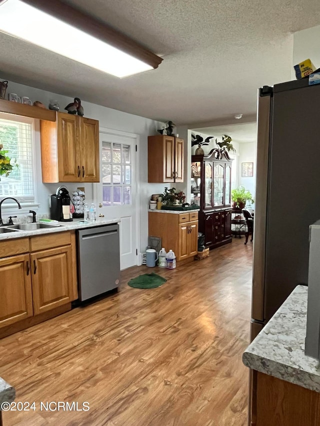 kitchen with light hardwood / wood-style flooring, appliances with stainless steel finishes, sink, and a textured ceiling