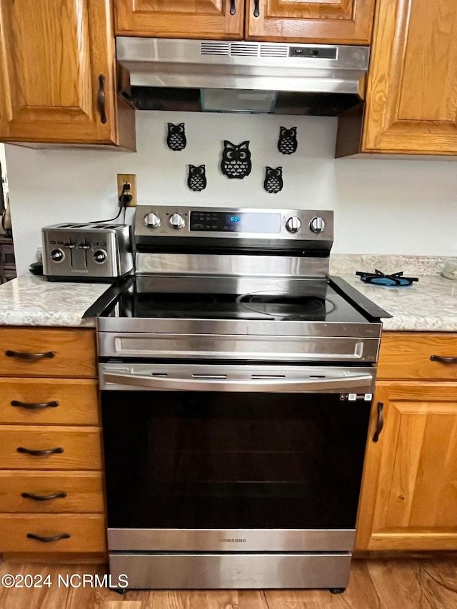 kitchen featuring light stone countertops, stainless steel range with electric cooktop, and light hardwood / wood-style flooring