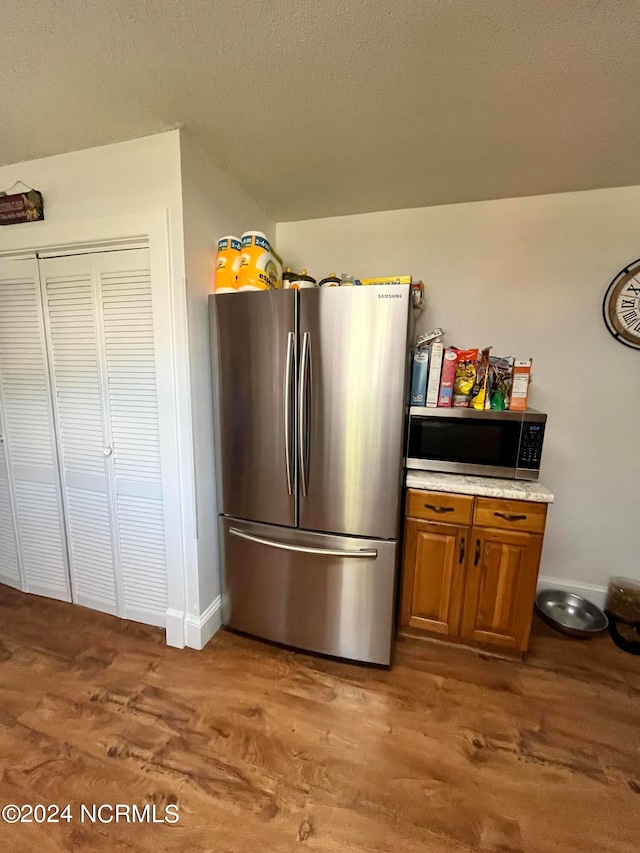 kitchen with a textured ceiling, appliances with stainless steel finishes, and hardwood / wood-style floors