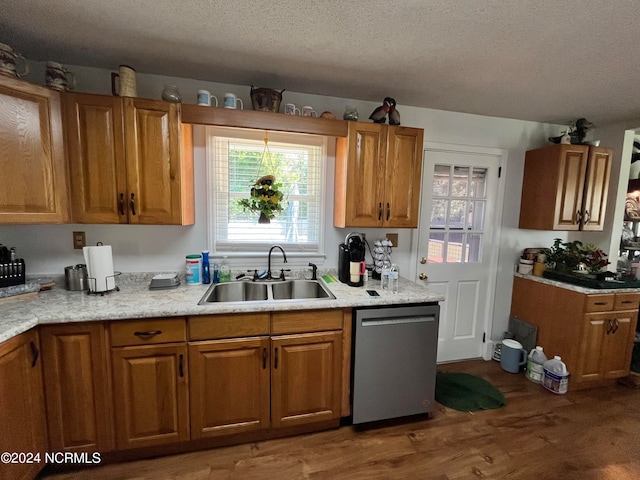 kitchen with light wood-type flooring, sink, stainless steel dishwasher, and a textured ceiling