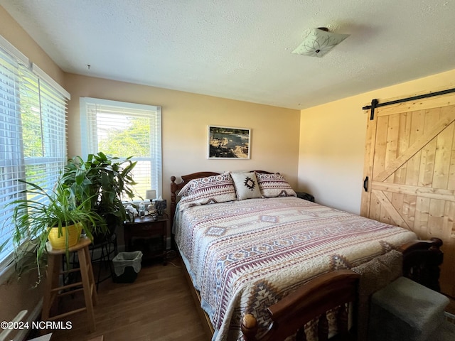 bedroom featuring a textured ceiling, dark hardwood / wood-style floors, and a barn door