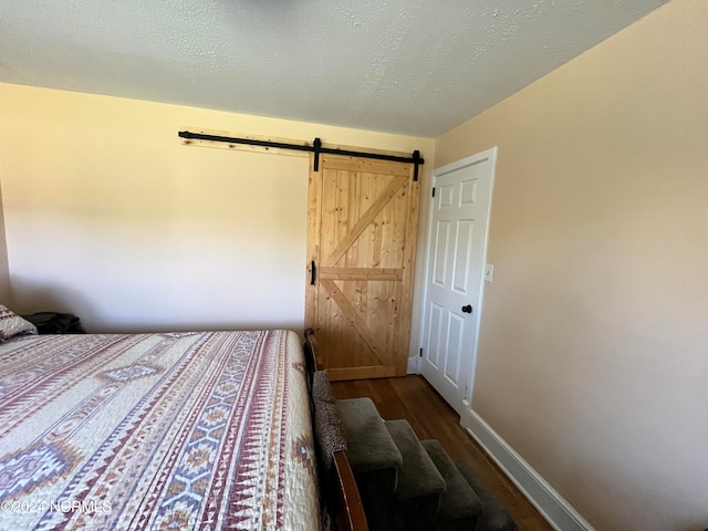 unfurnished bedroom featuring a barn door, hardwood / wood-style floors, and a textured ceiling