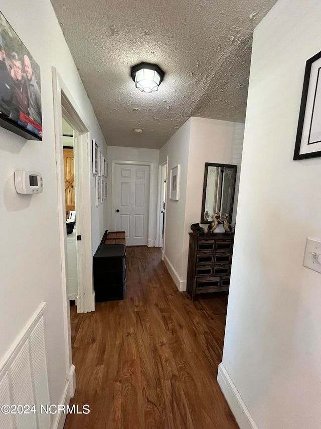 hall featuring a textured ceiling and dark hardwood / wood-style flooring