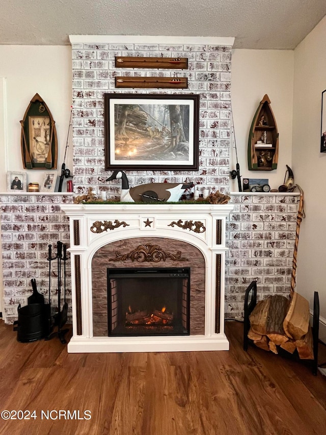 interior details with a brick fireplace, wood-type flooring, and a textured ceiling