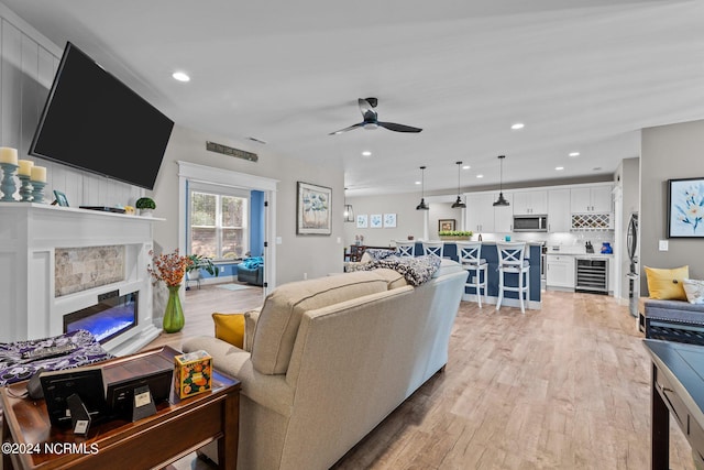 living room featuring light hardwood / wood-style floors, beverage cooler, and ceiling fan