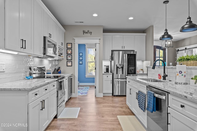 kitchen with white cabinetry, light hardwood / wood-style flooring, sink, decorative light fixtures, and stainless steel appliances