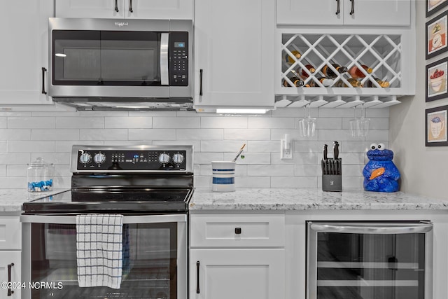 kitchen with beverage cooler, light stone counters, backsplash, white cabinetry, and stainless steel appliances