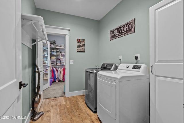 clothes washing area featuring washer and clothes dryer and light wood-type flooring