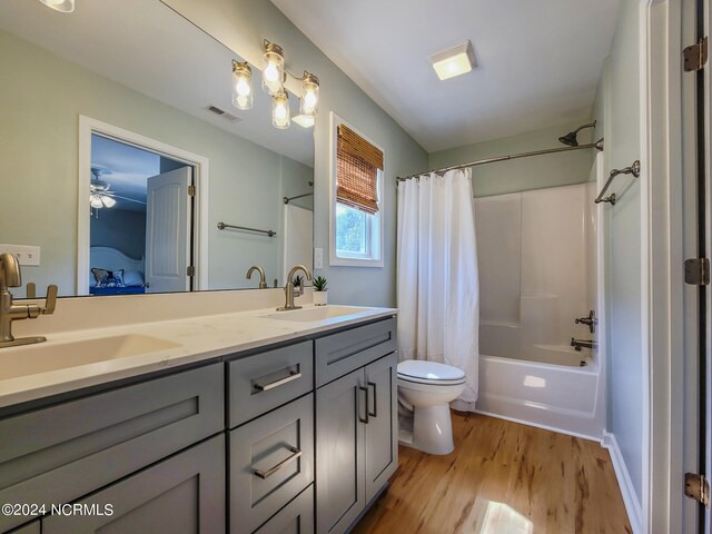 full bathroom with ceiling fan, shower / tub combo with curtain, hardwood / wood-style floors, vanity, and toilet