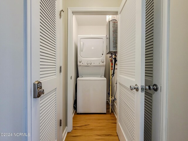 laundry area with light wood-type flooring and stacked washing maching and dryer