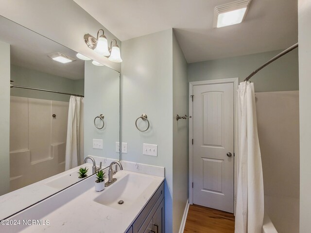 bathroom with shower / tub combo, hardwood / wood-style floors, and vanity