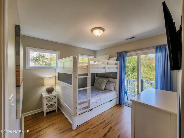 bedroom featuring light wood-type flooring, multiple windows, and access to exterior