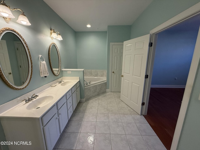 bathroom with vanity, a relaxing tiled tub, and tile patterned floors