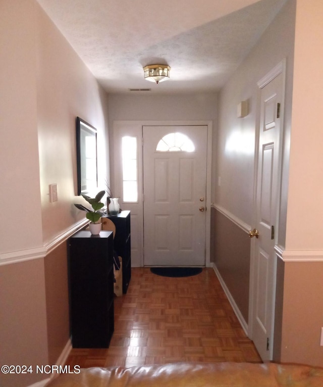 entryway with a textured ceiling and parquet floors