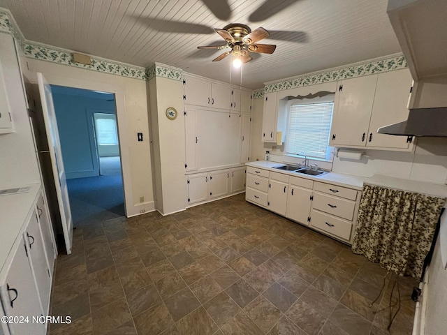 kitchen with ceiling fan, white cabinets, sink, and range hood