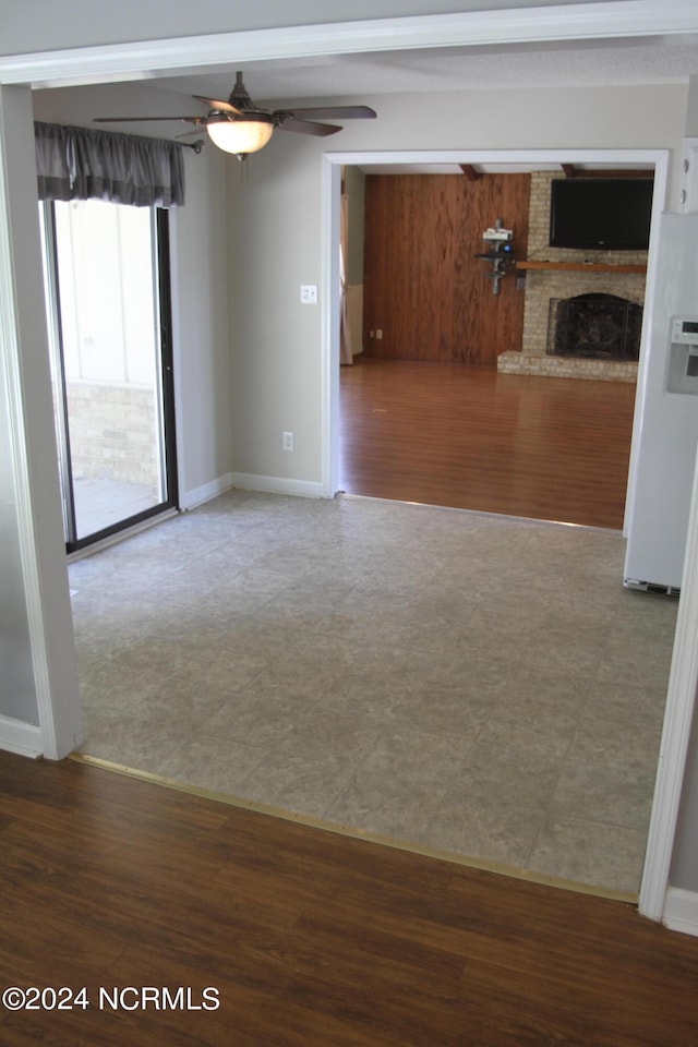 empty room featuring ceiling fan, a fireplace, and wood-type flooring