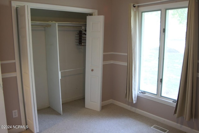 unfurnished bedroom featuring light carpet, a closet, and multiple windows